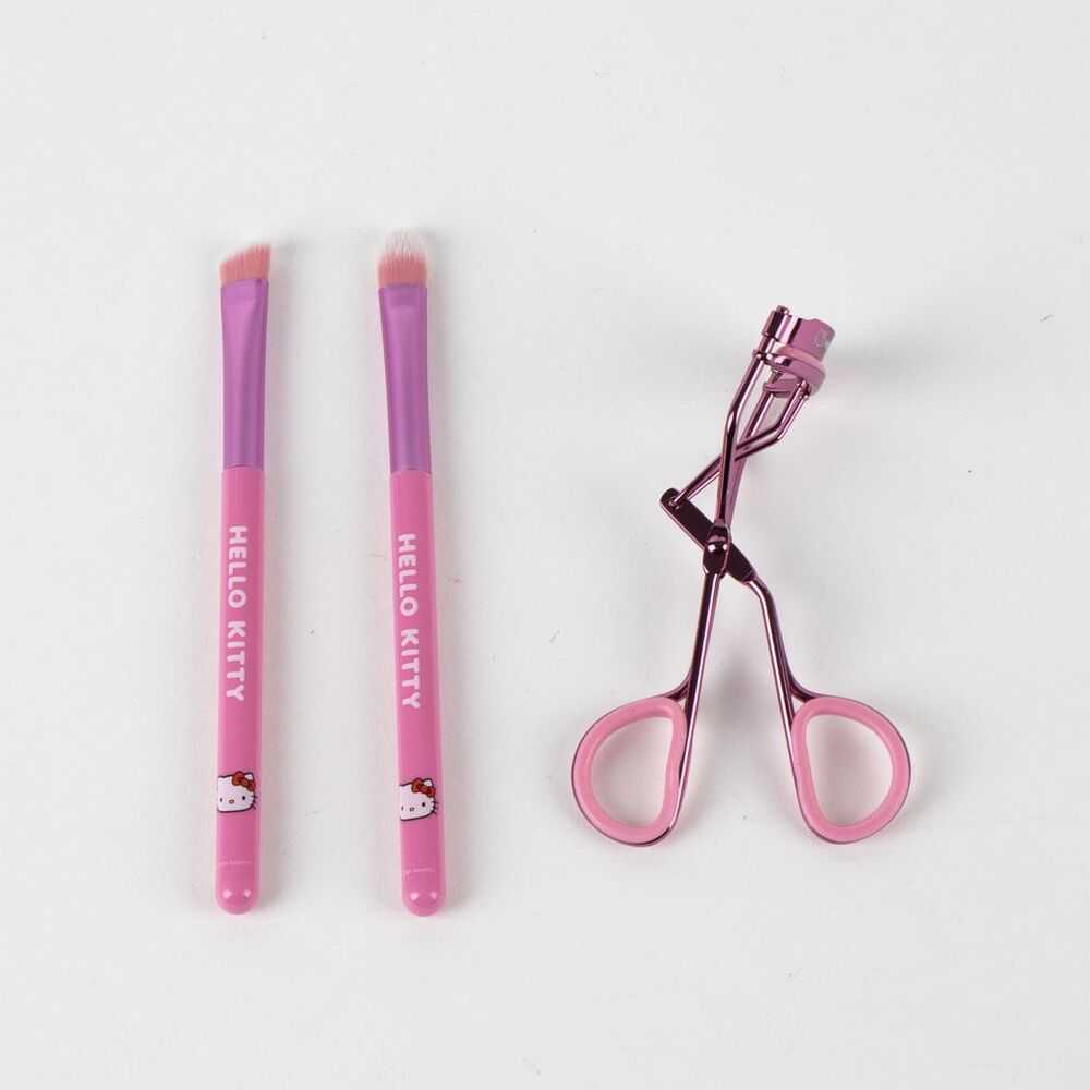 Set makeup Hello Kitty: due pennelli rosa e un piegaciglia viola su fondo bianco, Nerdscape
